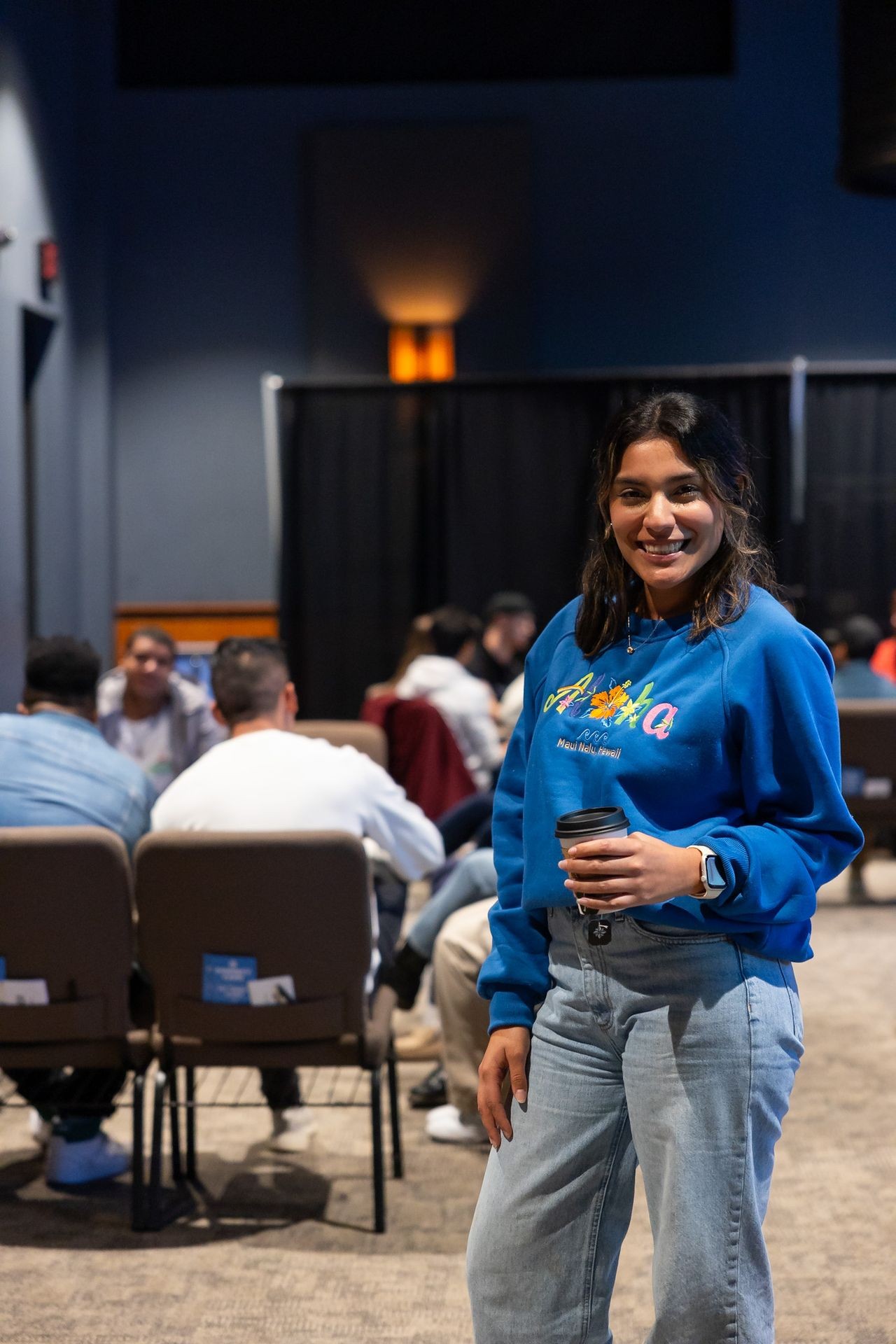 girl standing in front of a group people holding a coffee